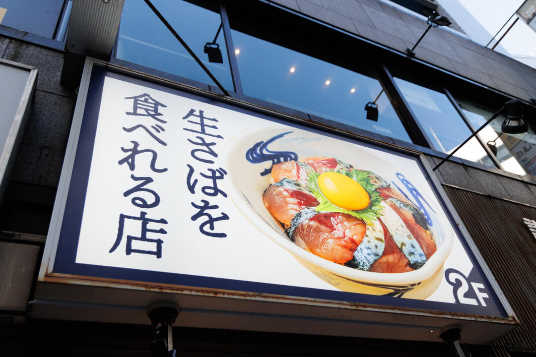 「生さばを食べれる店」の文字と写真が載っている看板の写真